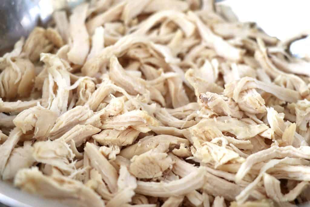 Cooked chicken that is shredded on a cutting board.