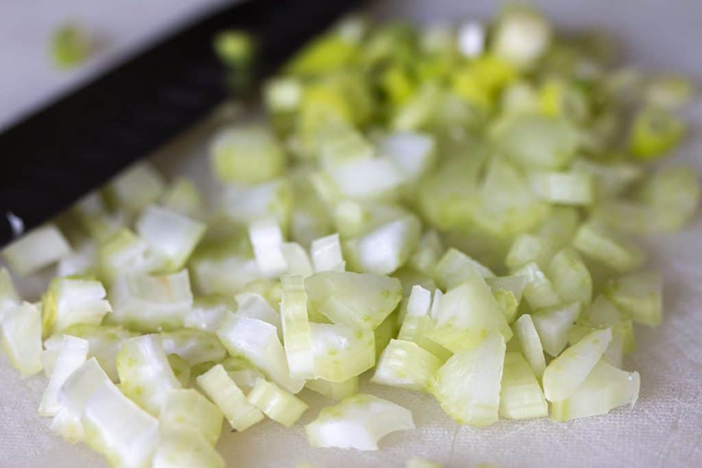 chopped celery on a cutting board with a knife