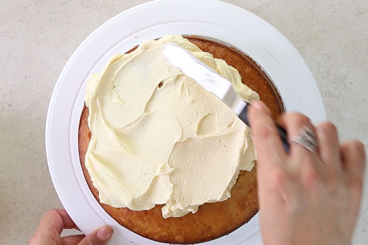 The frosting being spread over the cake