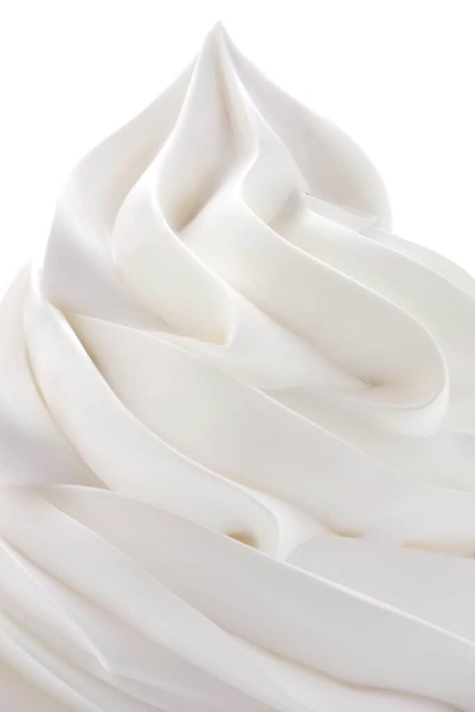 A close up of a swirl of whipped cream with a black background