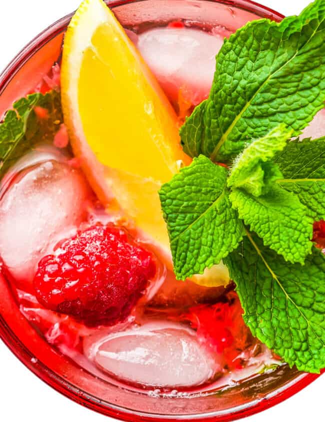 An overhead view of a raspberry mojito with ice and a sprig of mint