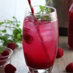 A straw and sprig of mint with ice and raspberry mojito