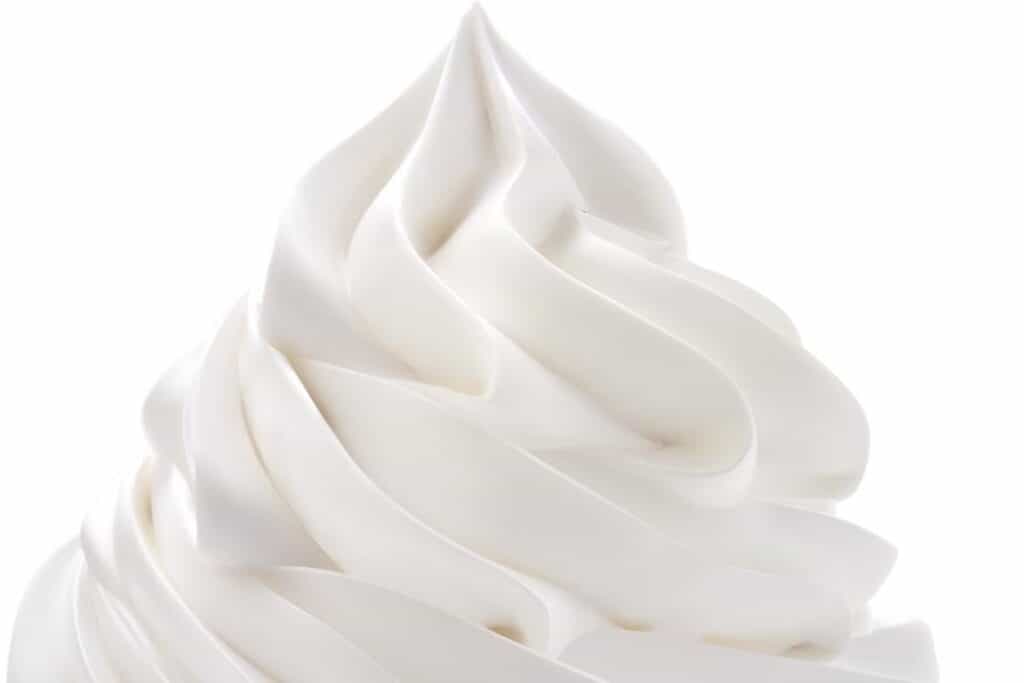 A close up of whipped cream swirled onto a surface with a white background