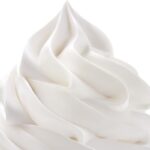 A close up of whipped cream swirled onto a surface with a white background