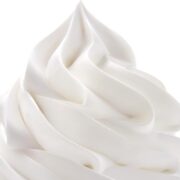 A close up of whipped cream swirled onto a surface with a white background