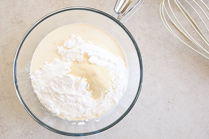 The whipping cream, sugar, powdered milk and vanilla added to a bowl.