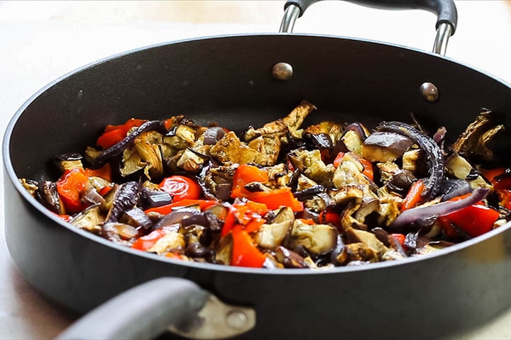 The roasted vegetables added to the pan