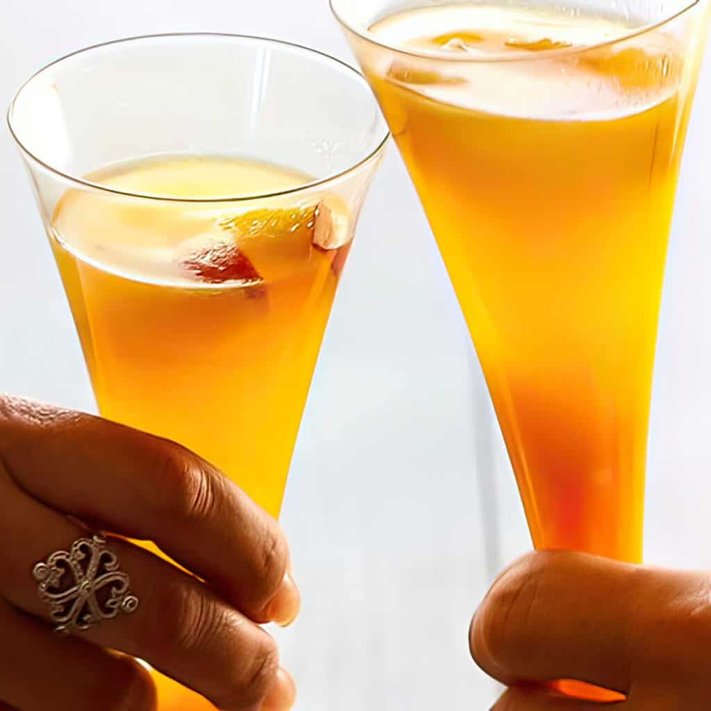 two glasses of Bellini Cocktail clinking together