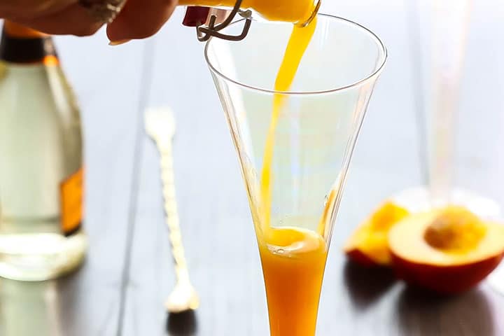 peach puree being added to a flute glass
