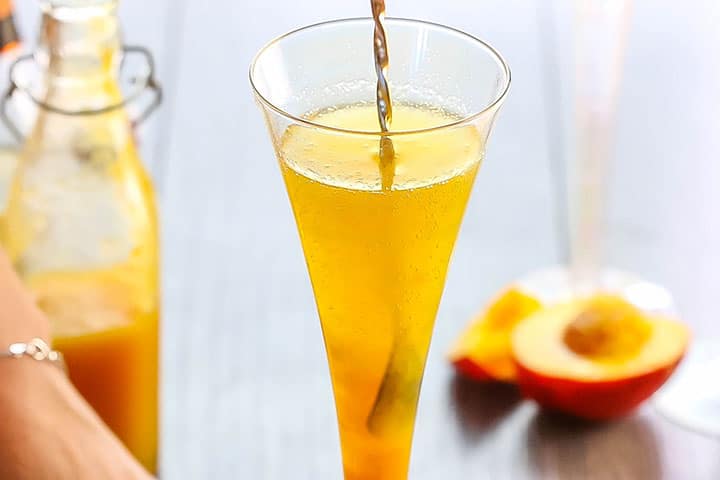 A long cocktail spoon stirring the Bellini Cocktail