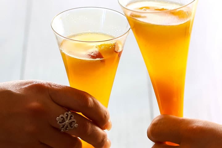 two glasses of Bellini Cocktail clinking together