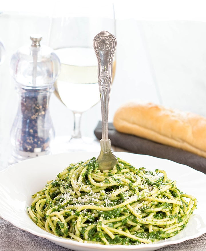 A bowl of Spaghetti with Spinach Sauce with a fork twirling the pasta around it.