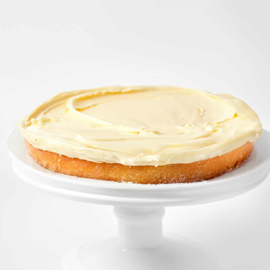 the buttercream spread over the bottom layer of the Victoria Sponge Cake