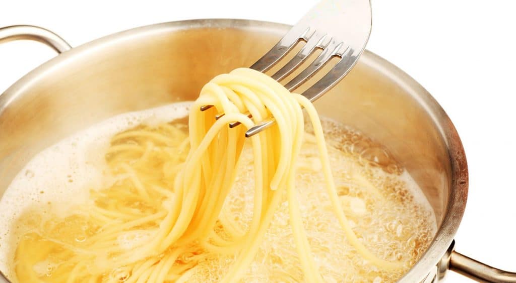 a pot of spaghetti cookng in water with a fork taking some out