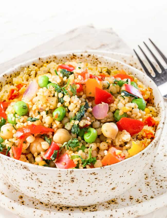 Close up view of a bowl full of Vegetable Moroccan Couscous with vibrant vegetables