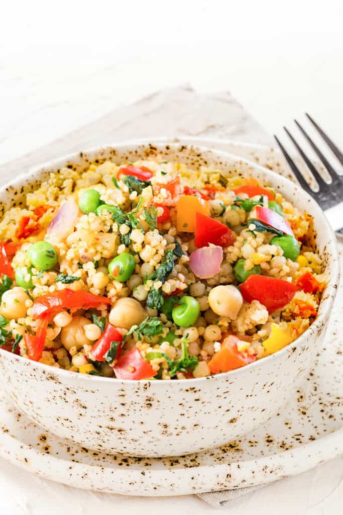 Close up view of a bowl full of Vegetable Moroccan Couscous with vibrant vegetables