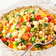 a close up image of Vegetable Moroccan Couscous in a bowl with a serving spoon