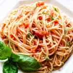 A photo taken from above of a plate of spaghetti with tomato sauce with a fork next to it