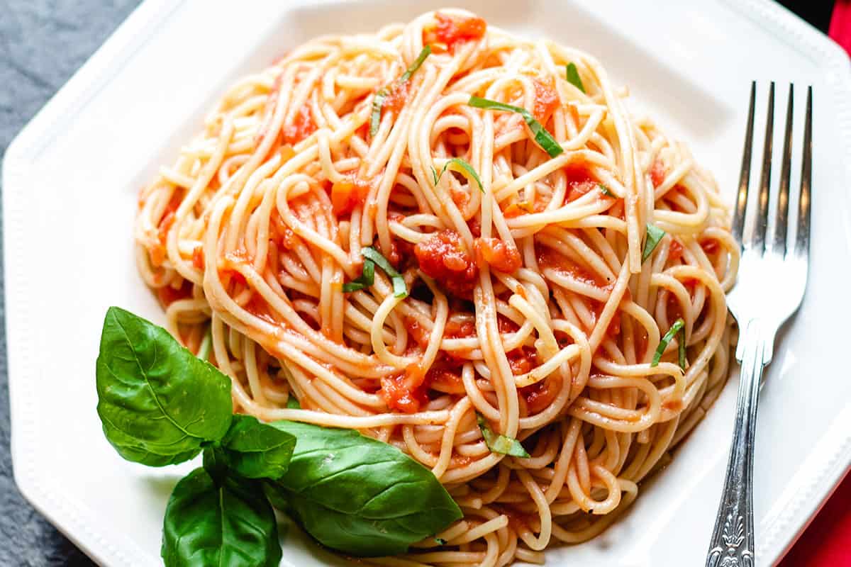 A photo taken from above of a plate of spaghetti with tomato sauce with a fork next to it