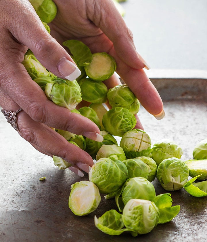 the prepared Brussels sprouts being placed on a sheet pan