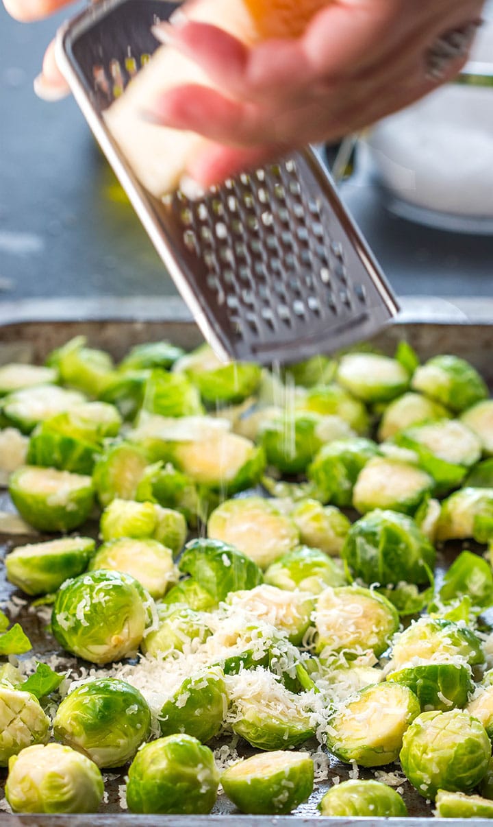 Parmesan cheese being grated onto the Brussels Sprouts in the pan