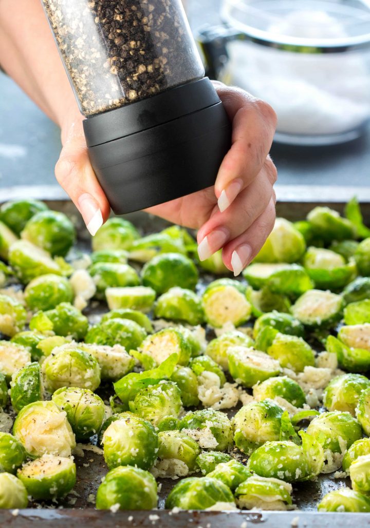 Fresh ground pepper being grated onto the Brussels Sprouts in the pan