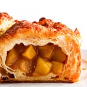 Apple Turnovers on a plate with a close up of one broken open to show the apple filling.