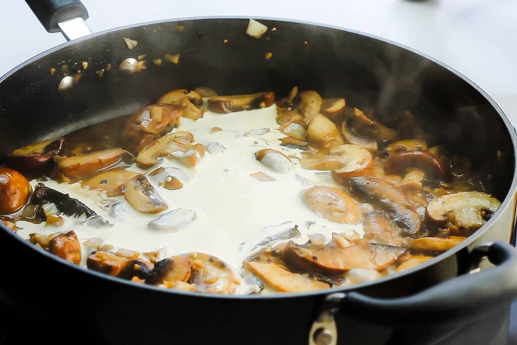 The cream added to the mushroom mixture in the pan.