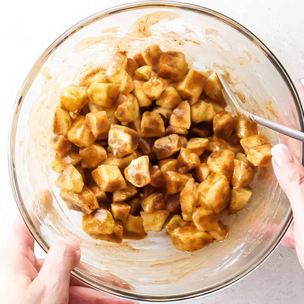 the apples coated in the sugar and spice mix in a glass bowl.