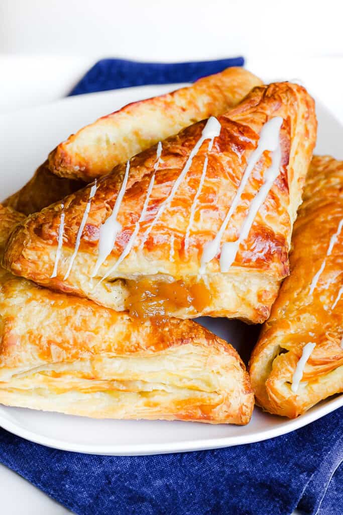 a platter of puff pastry apple turnovers with a drizzle of icing.