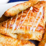 a platter piled high with apple turnovers drizzled with icing.