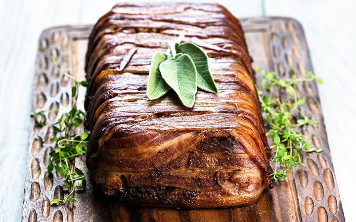 The Bacon Wrapped Sausage Stuffing on a cutting board ready to slice