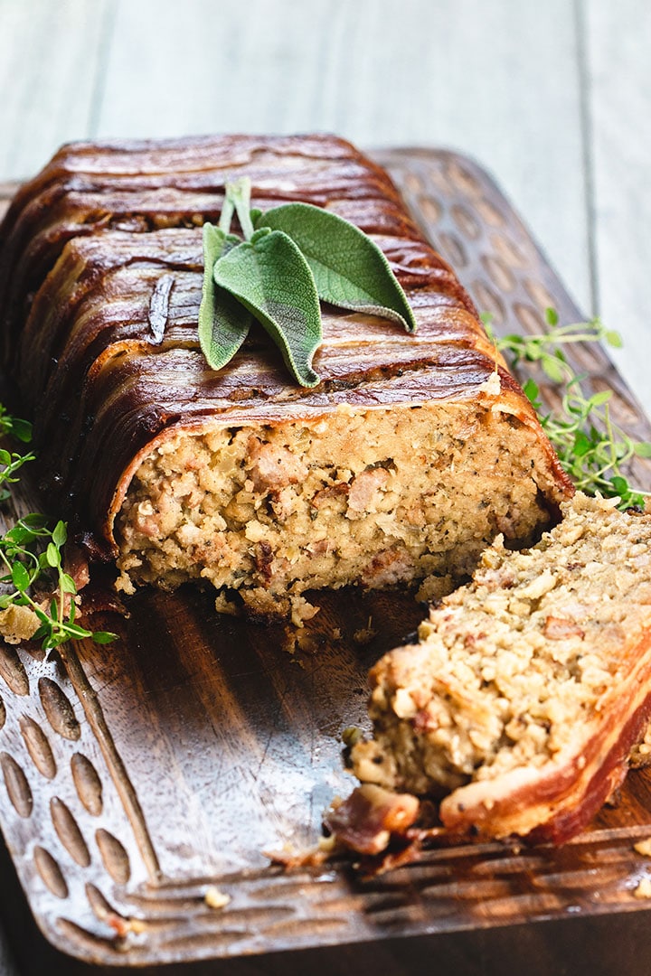 Bacon Wrapped Sausage Stuffing with a slice cut out of it showing the stuffing with sausage meat throughout