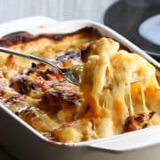 A spoon serving Cheesy Cauliflower from a pan.
