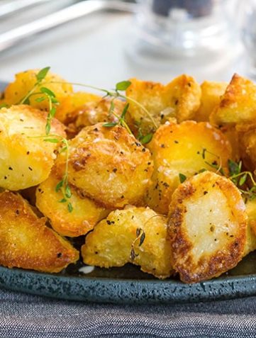 A dish piled high with golden, Crispy Roast Potatoes