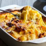 Cheesy Cauliflower Casserole being scooped from the pan with strings of cheese hanging from the spoon