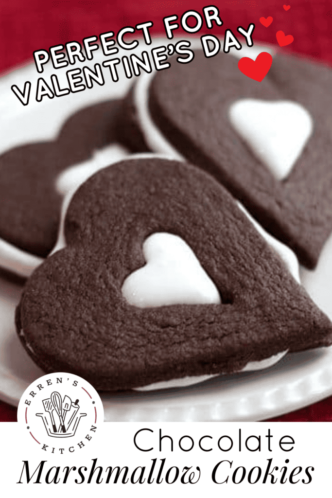 Three chocolate sandwich cookies shaped like hearts with a heart cutout in the center and white marshmallow filling puffing out of the heart center.