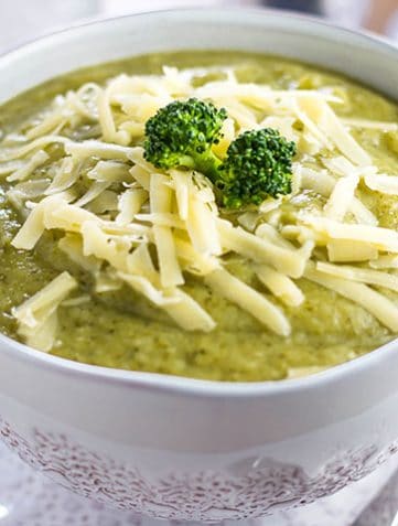 a Bowl full of Healthy creamy broccoli soup with shredded cheese and broccoli on top