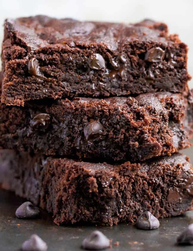 A stack of three double chocolate chip bars with melted chocolate chip cookies dotted throughout