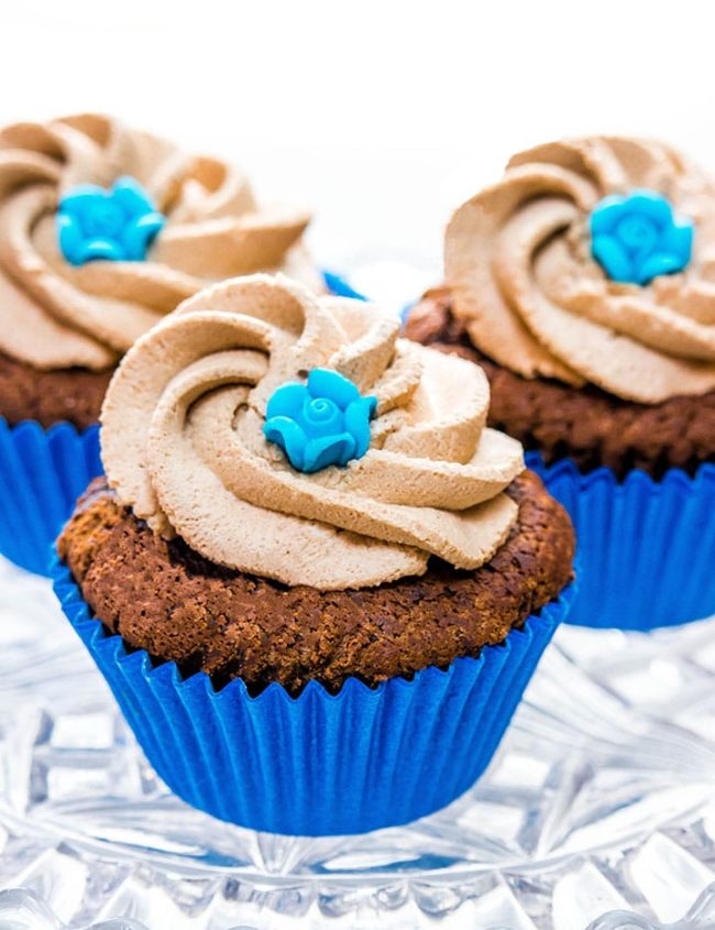Three chocolate cupcakes with Chocolate Whipped Cream Frosting and decorated with little blue roses