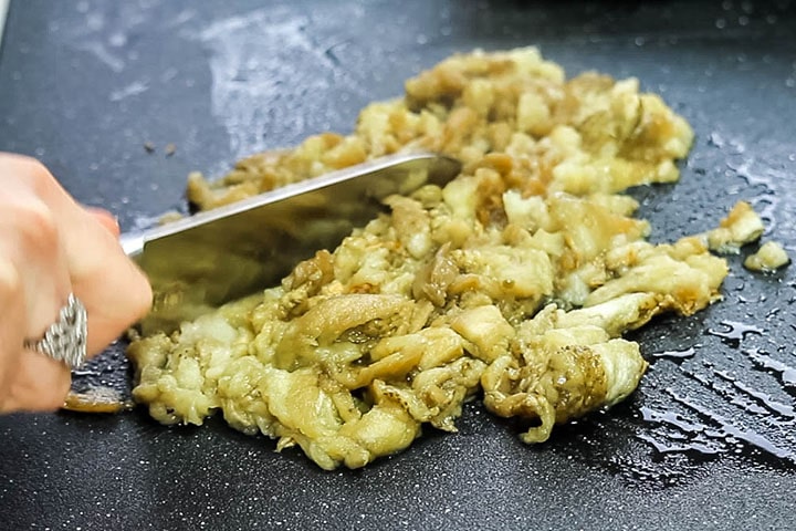 The flesh of the eggplant being chopped with a knife