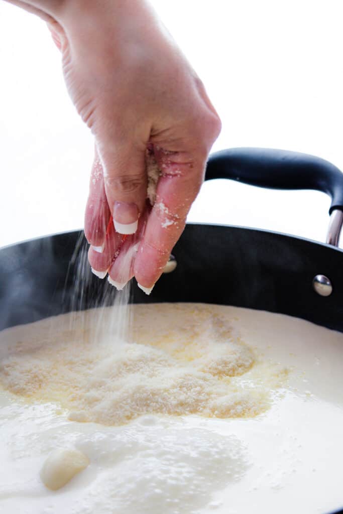 The cheese being added to the sauce in the pan