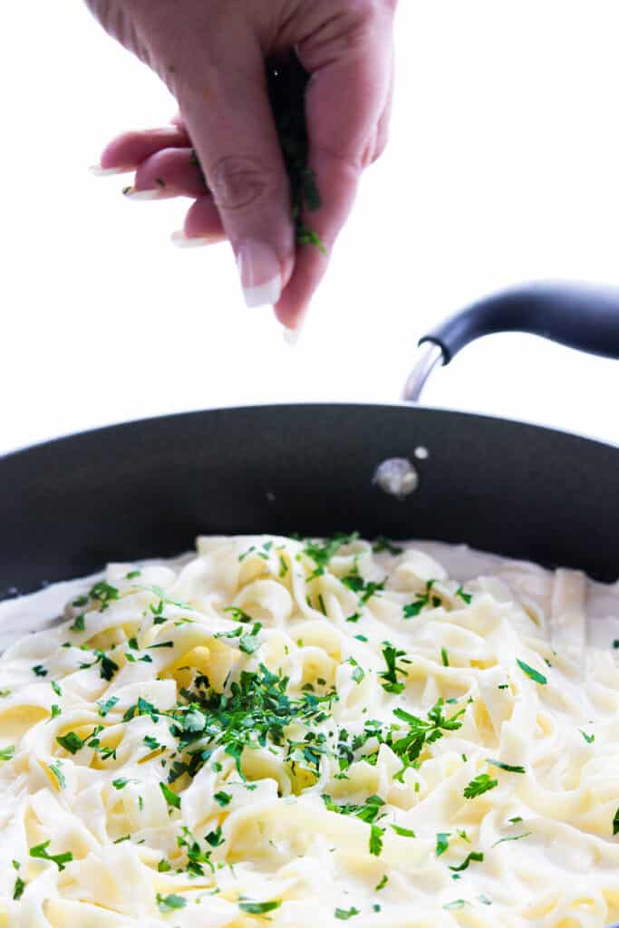 parsley added to the pan of Fettuccine Alfredo 