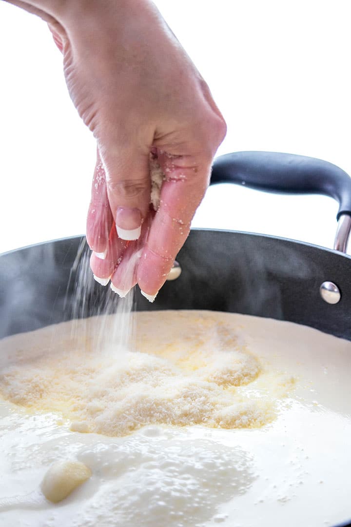 The cheese being added to the sauce in the pan