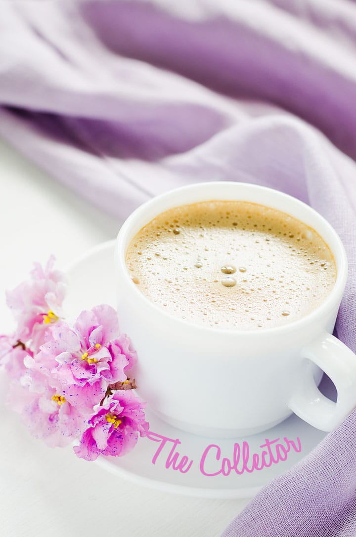 White cup of morning coffee or cappuccino and delicate pink, purple, lilac flowers.