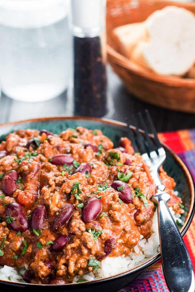 A bowl of food on a plate, with Chili con carne and beef