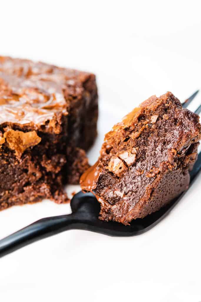 a fork with a piece of Fudgy Chocolate Chip Brownie on it with the rest in the background