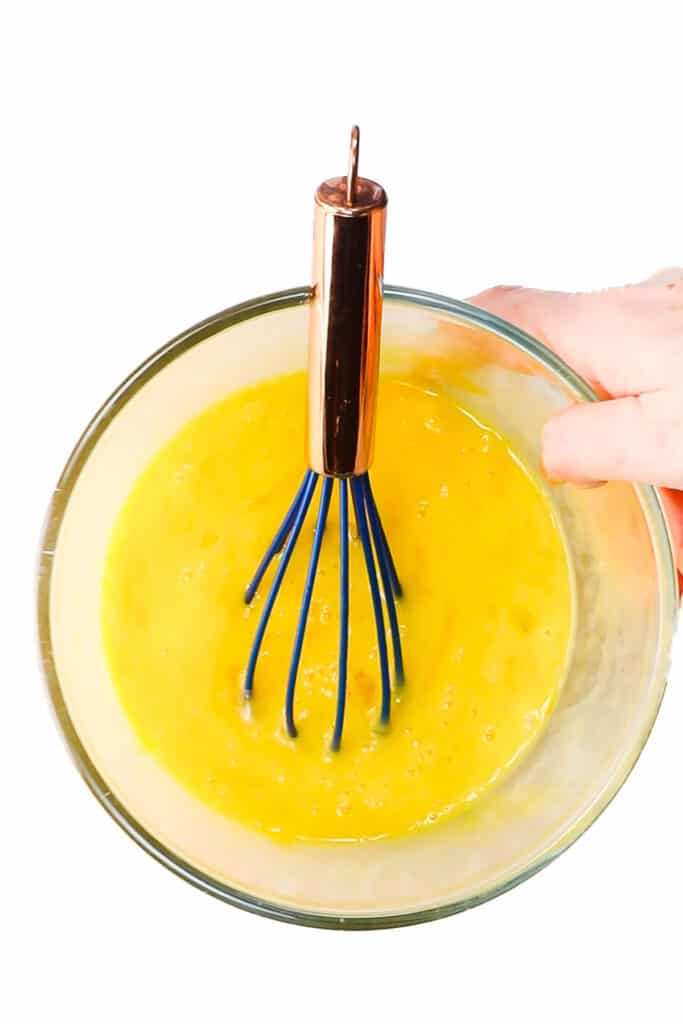 a bowl of beaten eggs with the whisk