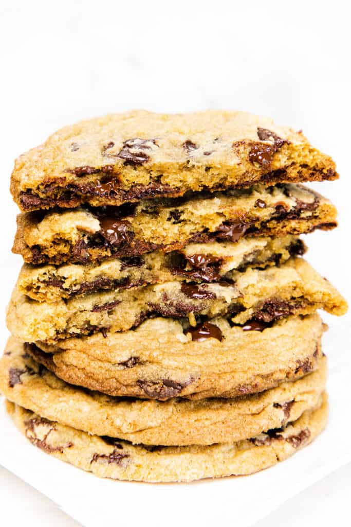 a pile of chocolate chip cookies broken open to expose the inside of the cookies