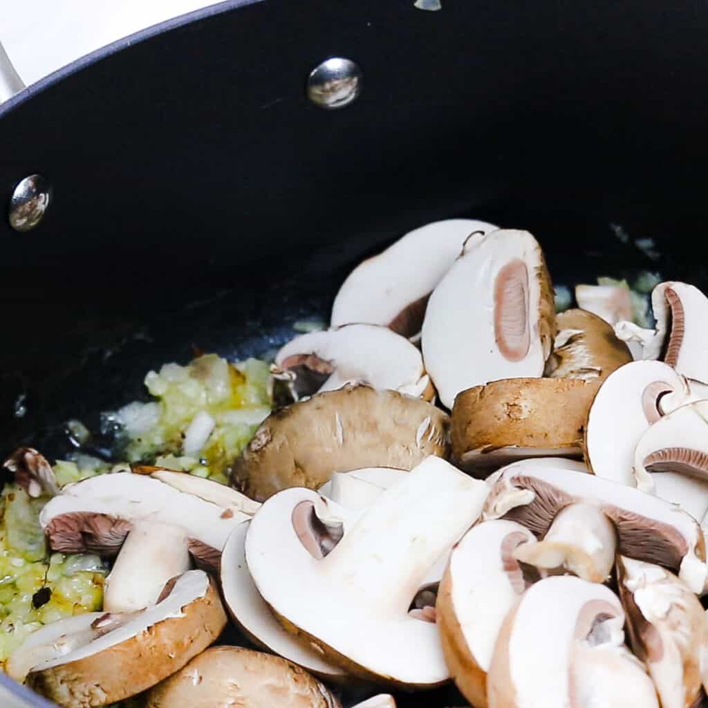 Mushrooms cooking in a pot with garlic and shallots